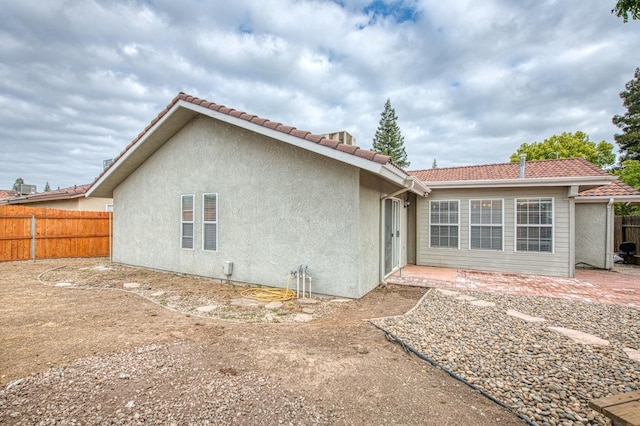 5711 W Fallon Ave, Fresno, CA 93722 - rear view of property featuring stucco siding, a tiled roof, a patio, and fence