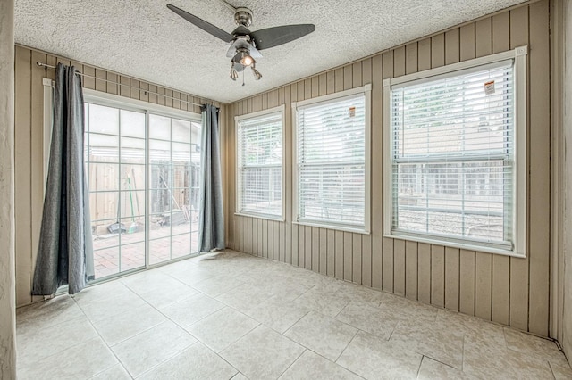 5711 W Fallon Ave, Fresno, CA 93722 - spare room with light tile patterned flooring, a textured ceiling, a ceiling fan, and wood walls