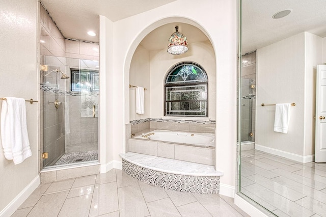 bathroom with baseboards, a bath, tile patterned flooring, and a stall shower