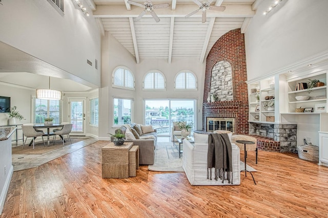 living room featuring high vaulted ceiling, wood finished floors, ceiling fan, beamed ceiling, and a brick fireplace