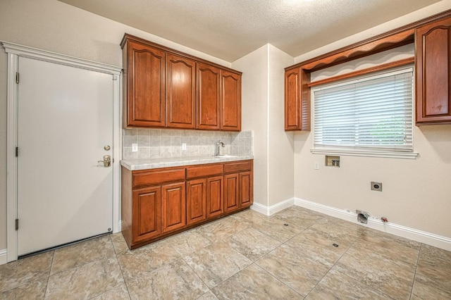 washroom with a sink, hookup for an electric dryer, gas dryer hookup, hookup for a washing machine, and a textured ceiling