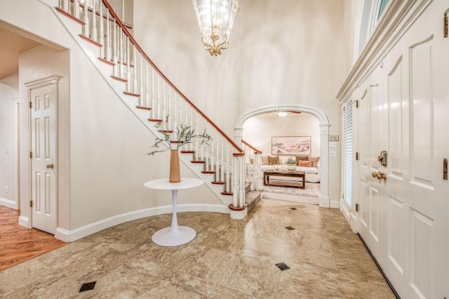entrance foyer with baseboards, a towering ceiling, and stairs