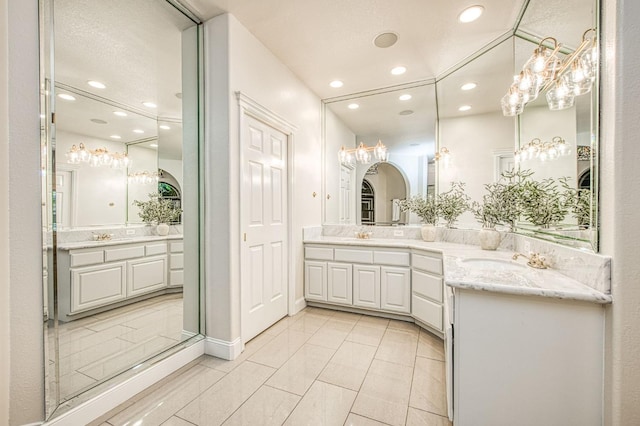 bathroom featuring a notable chandelier, tile patterned flooring, two vanities, and recessed lighting