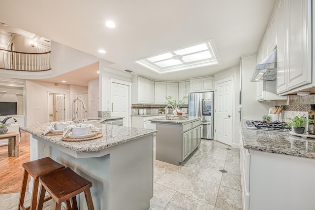 kitchen featuring stainless steel appliances, a kitchen island, tasteful backsplash, and wall chimney range hood