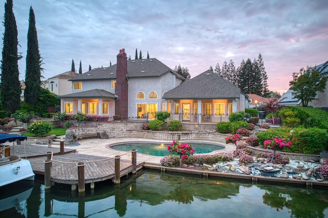 back of property featuring stucco siding, a chimney, an outdoor pool, and a patio area