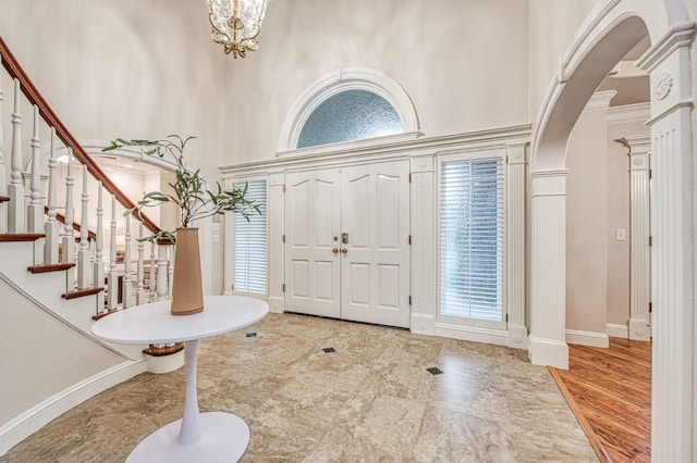 entryway featuring baseboards, a high ceiling, arched walkways, and ornate columns