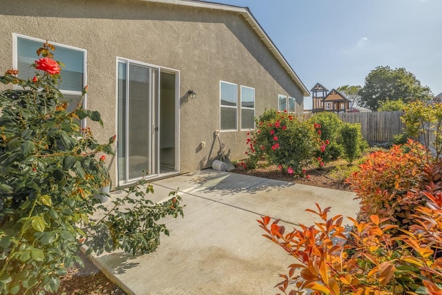 rear view of property with fence, stucco siding, and a patio