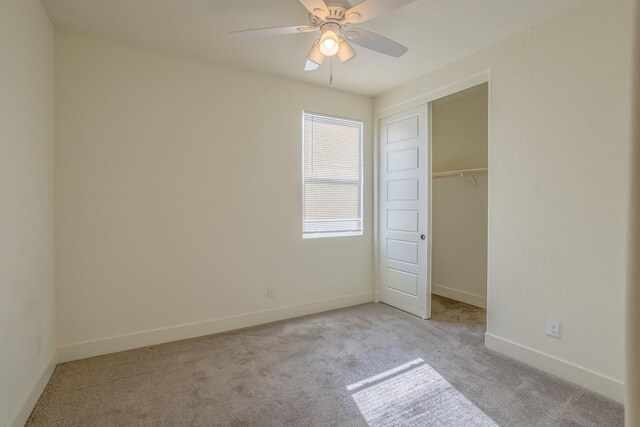 unfurnished bedroom featuring light colored carpet, ceiling fan, baseboards, and a closet