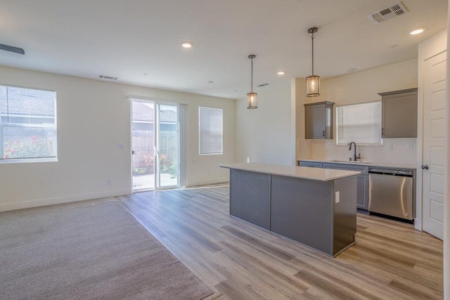 kitchen with a center island, a sink, dishwasher, light countertops, and visible vents