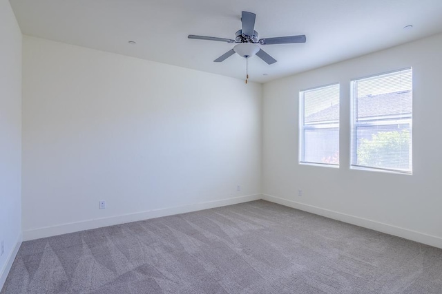 carpeted empty room featuring baseboards and ceiling fan