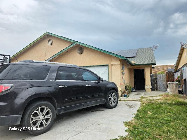 21754 California, San Joaquin, CA 93660 - view of front of home with fence, an attached garage, stucco siding, solar panels, and driveway