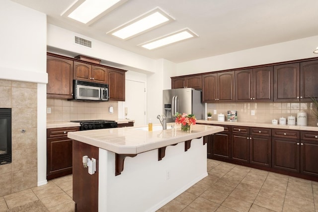 kitchen featuring a kitchen breakfast bar, a sink, light tile patterned floors, stainless steel appliances, and visible vents