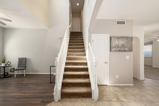 staircase with visible vents, baseboards, and ceiling fan