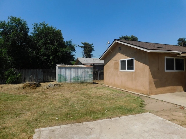 exterior space featuring stucco siding, a yard, a patio, and fence