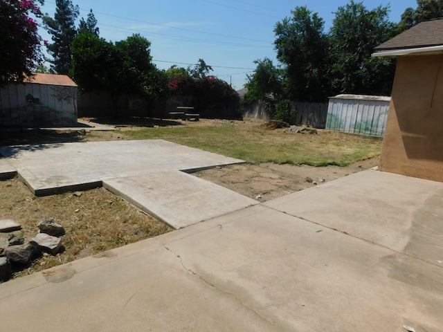 view of yard featuring an outdoor structure, a shed, a patio, and fence