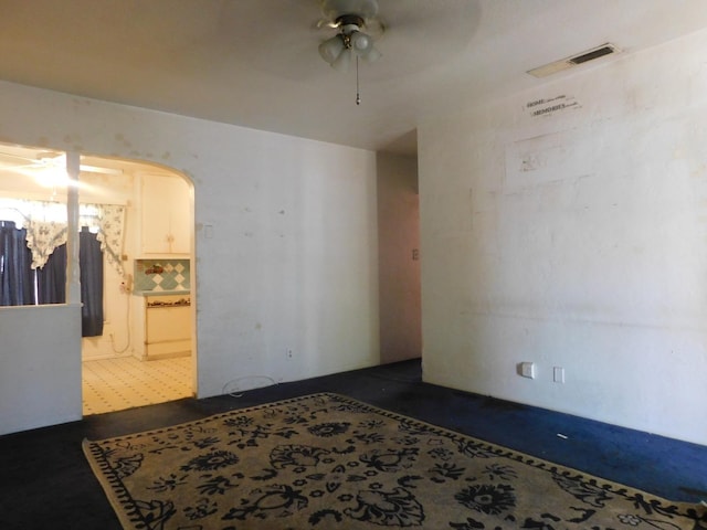 empty room with ceiling fan, arched walkways, and visible vents