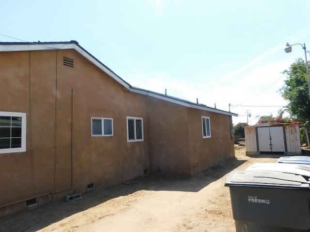 view of home's exterior featuring a storage shed, an outbuilding, crawl space, and stucco siding