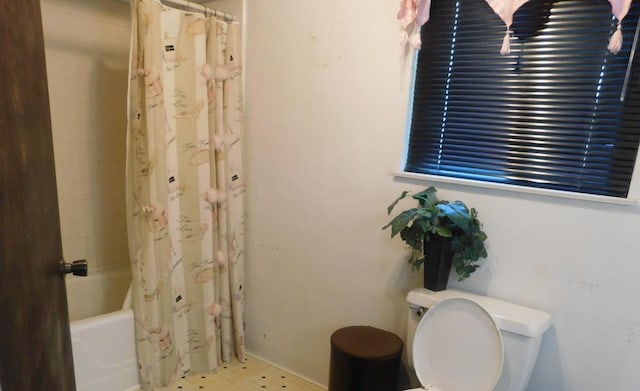 bathroom featuring toilet and shower / bath combination with curtain