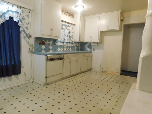 kitchen with baseboards, backsplash, white cabinetry, light floors, and light countertops