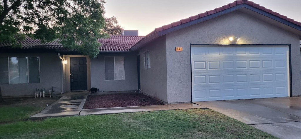 6311 N Barcus, Fresno, CA 93722 - ranch-style home with a tiled roof, stucco siding, concrete driveway, and a garage