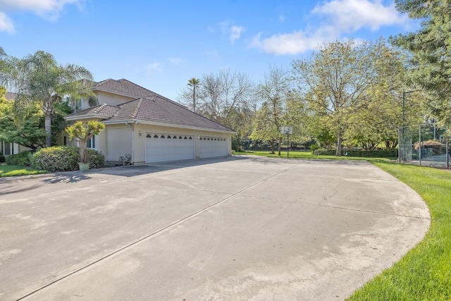 view of property exterior featuring stucco siding, an attached garage, driveway, and a tiled roof