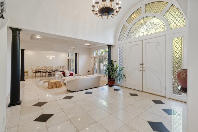 foyer entrance featuring a high ceiling, ornate columns, a notable chandelier, and light tile patterned floors