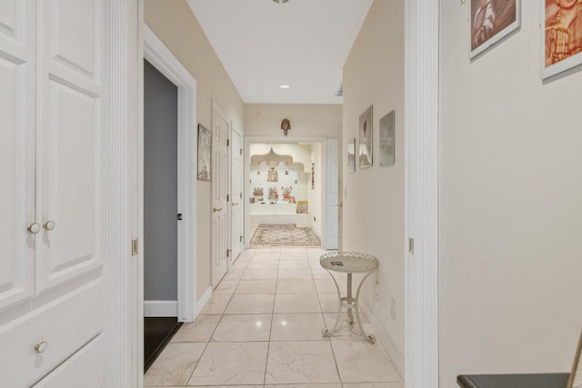 hall featuring baseboards, recessed lighting, and light tile patterned floors