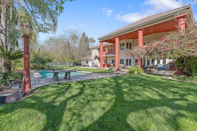 view of yard with a patio area, an outdoor pool, a balcony, and a ceiling fan