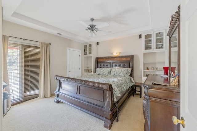 bedroom featuring light carpet, a ceiling fan, visible vents, and a raised ceiling