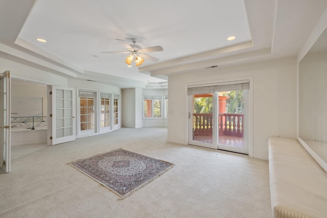 interior space with a tray ceiling, carpet floors, visible vents, and ceiling fan
