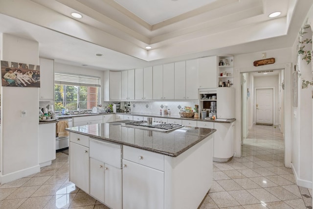 kitchen with a center island, stainless steel gas stovetop, a raised ceiling, white cabinets, and recessed lighting