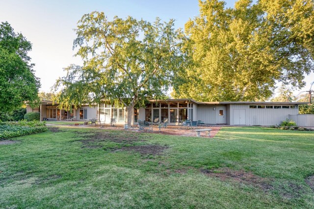 rear view of house featuring a lawn and a patio area