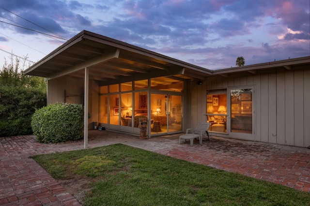back of property at dusk featuring a patio area and a yard