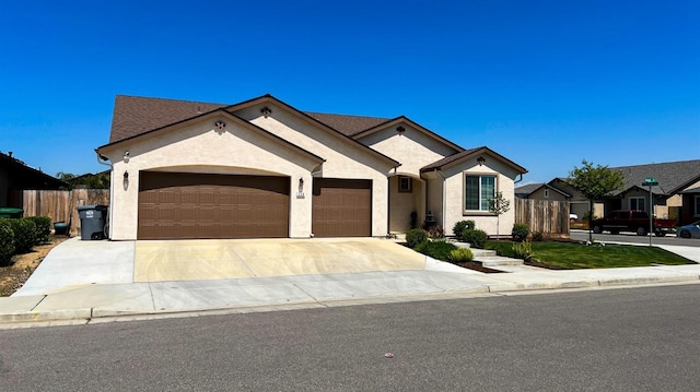 view of front of home featuring an attached garage, driveway, fence, and stucco siding