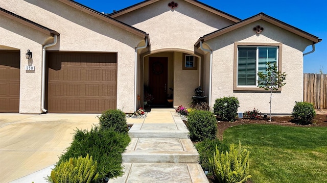 view of front of house with a garage, driveway, fence, a front yard, and stucco siding