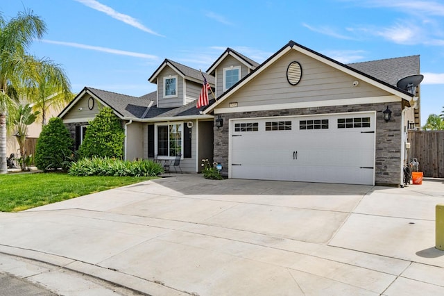 view of front of property with fence, a shingled roof, driveway, stone siding, and a garage