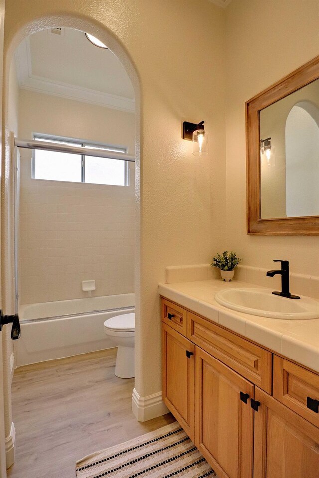 full bathroom featuring wood finished floors, bathtub / shower combination, ornamental molding, toilet, and vanity