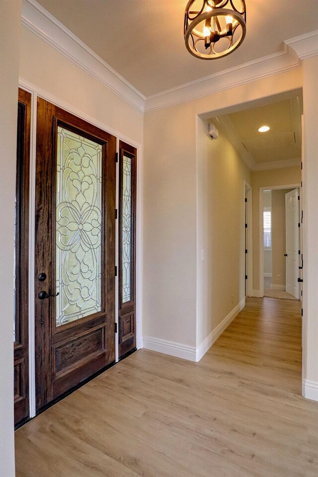 foyer featuring baseboards, ornamental molding, and light wood-style flooring