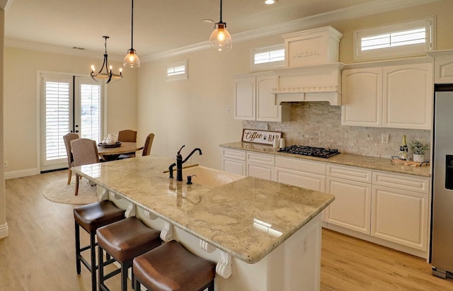 kitchen with white cabinetry, tasteful backsplash, light wood-type flooring, and light stone counters