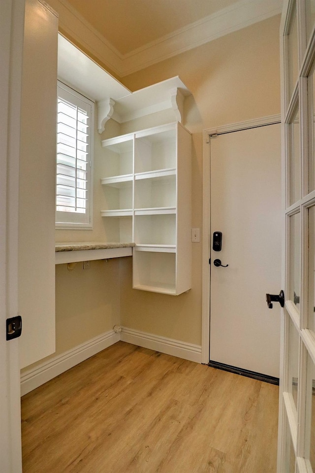 entryway with crown molding, baseboards, and light wood-type flooring