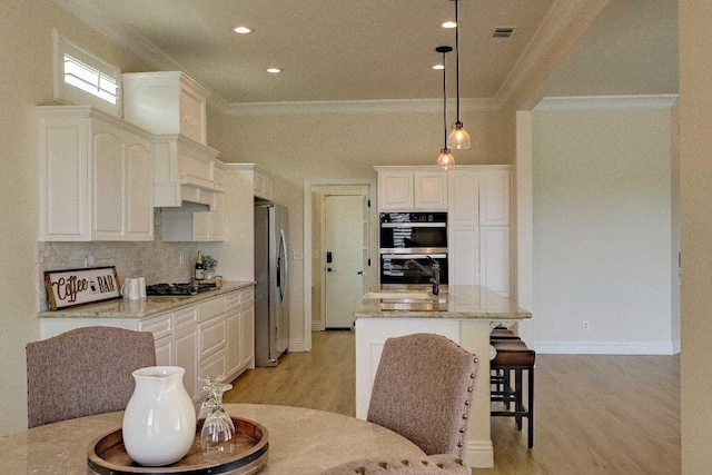 kitchen with light wood finished floors, light stone countertops, decorative backsplash, ornamental molding, and appliances with stainless steel finishes