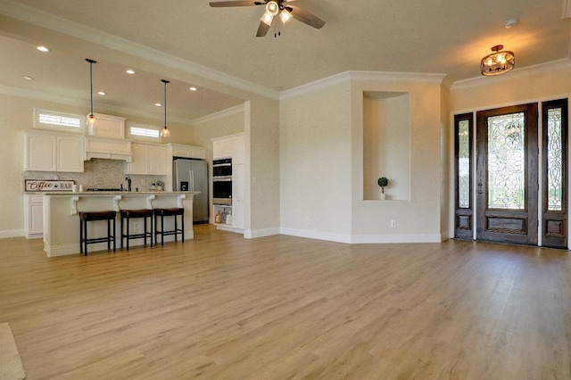 living area with recessed lighting, crown molding, a ceiling fan, light wood-style flooring, and baseboards
