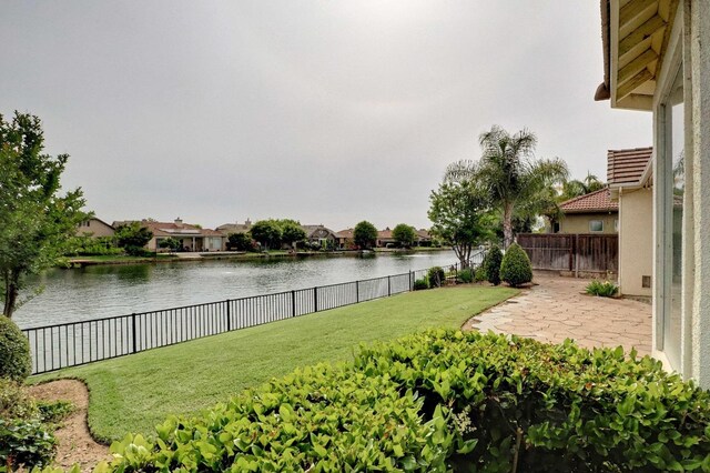 view of yard with a patio, a fenced backyard, and a water view