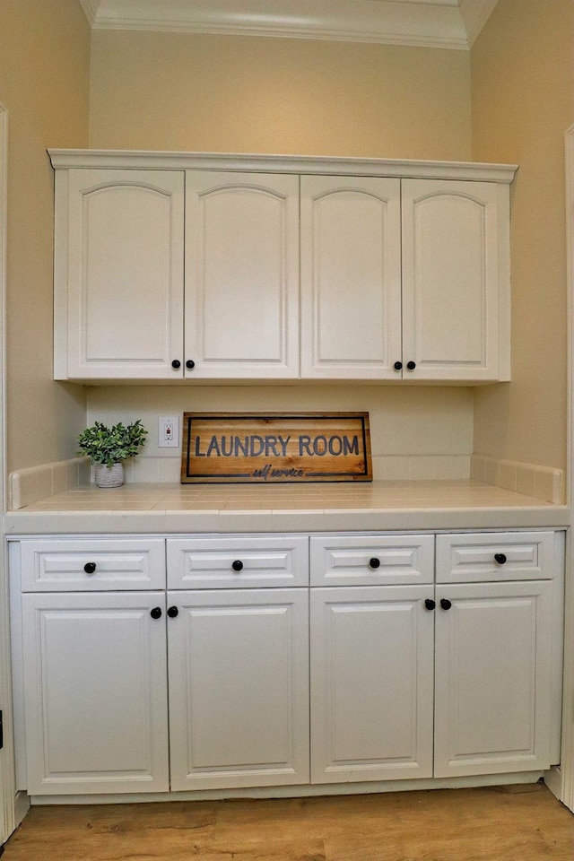 bar with light wood-style floors and crown molding