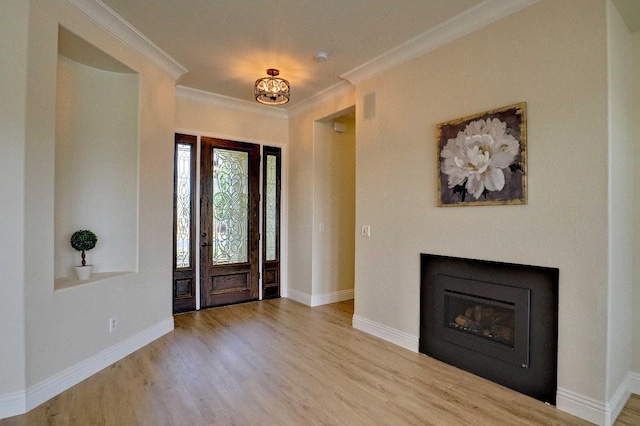 foyer entrance featuring baseboards, wood finished floors, crown molding, and a glass covered fireplace