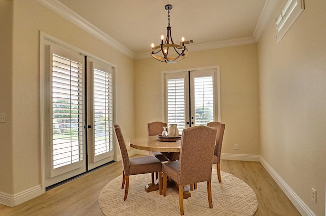dining room featuring light wood-type flooring, a notable chandelier, and french doors