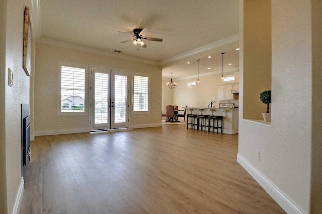 living room with crown molding, baseboards, wood finished floors, and ceiling fan with notable chandelier