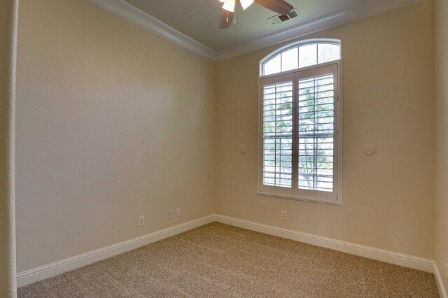 empty room with light colored carpet, baseboards, visible vents, a ceiling fan, and crown molding