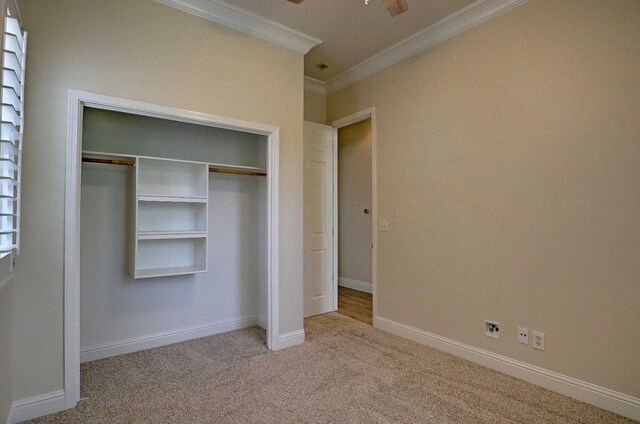 unfurnished bedroom featuring baseboards, ornamental molding, a closet, and carpet