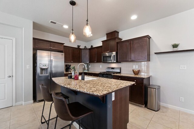 kitchen featuring stainless steel appliances, a sink, light tile patterned flooring, and light stone countertops